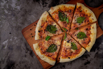 A slice of pizza with basil leaves on top. The pizza is cut into six pieces. The pizza is on a...