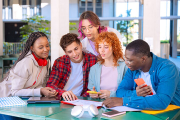 Multiracial group of five happy teenage students talking with university notes. and smartphones
