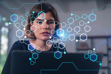 Woman working on laptop with holographic data overlay.