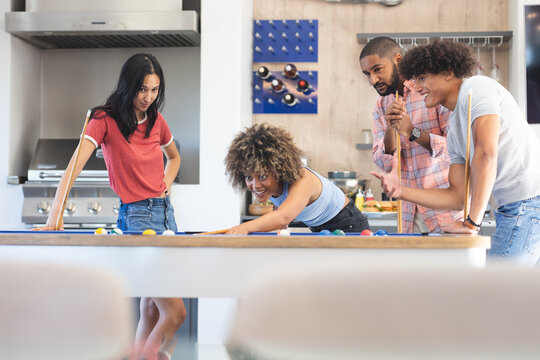 Playing board game, group of diverse friends enjoying time together in kitchen, at home