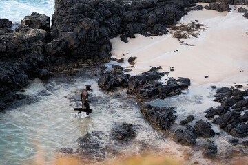 person in wetsuit on the rocky beach