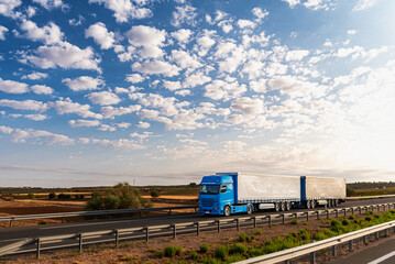Truck with two trailers, also called Duo-trailer, driving on a highway under a cloudy sky.