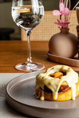 Spongy and exquisite cinnamon roll with sweet white sauce drizzled. Elegant hotel restaurant, gastronomy and desserts.