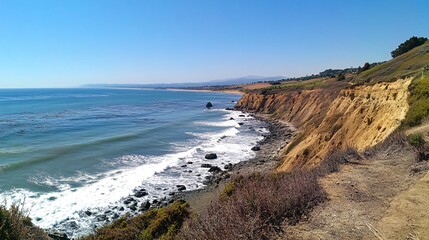 A panoramic view of a rugged coastline with crashing waves, a sandy beach, and lush greenery under a clear blue sky.