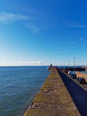 Obraz premium Looking down the traditional stone Breakwater of Arbroath East Pier towards the Harbour lighthouse and the tidal harbour area.