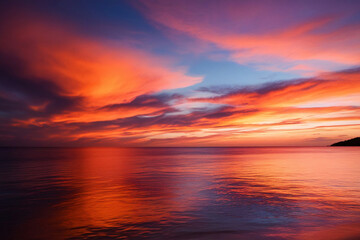 Fototapeta premium A breathtaking image of a vivid sunset casting warm hues of red, orange, and pink over the calm ocean waters. The vibrant colors blend seamlessly with the deep blue and purple of the sky