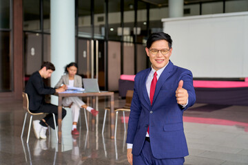 Asian businessman stand out from group and trump up for confirm quality of working team and...