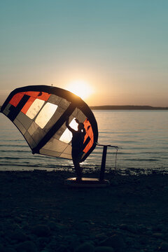 Man athlete comes out of the water with wing foil equipment at sunset.