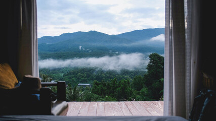 Fototapeta premium Greenery mountain view on foggy day outside wooden bedroom