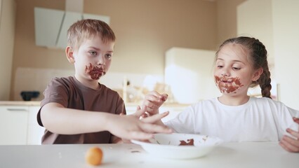 baby boy and girl eat chocolate. dirty little baby kids in the kitchen eating chocolate in the morning. happy family eating sweets kid dream concept. baby dirty face eating chocolate cocoa sweet