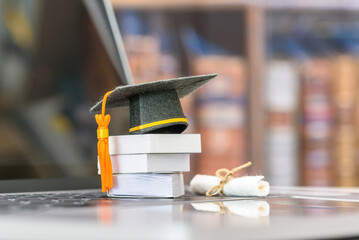 Graduate study abroad program to broaden learner's world view, e-learning concept : Graduation cap, foreign books on a laptop, depicts student attempting to study from a distance or learning from home