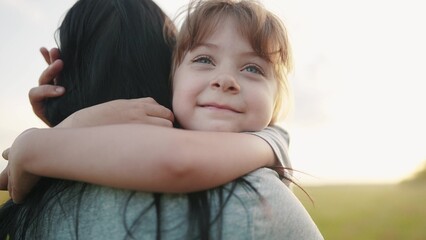 daughter hugging mom. happy family a kid dream concept. mother carries her daughter in her arms walk in the park in nature. child hugging mother neck. mother walks with a child in nature lifestyle