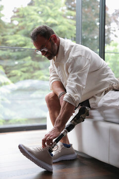 Man with artificial limb tying shoe