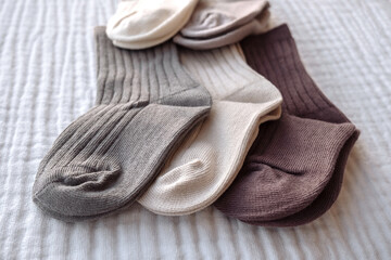 Children's socks of different colors are laid out on a white bedspread  
