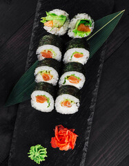 Sushi rolls set served on black stone slate with wasabi and ginger
