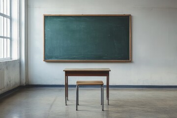 Minimalist classroom interior with large green chalkboard, wooden desk and chair, and sunlight from window