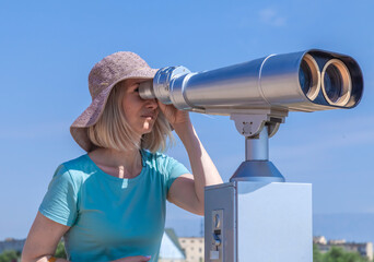 tourist using coin operated binoculars on high hill looking at cityscape