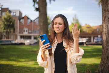 Beautiful upset woman walking outdoor in park. Sad angry female having talking conversation with...