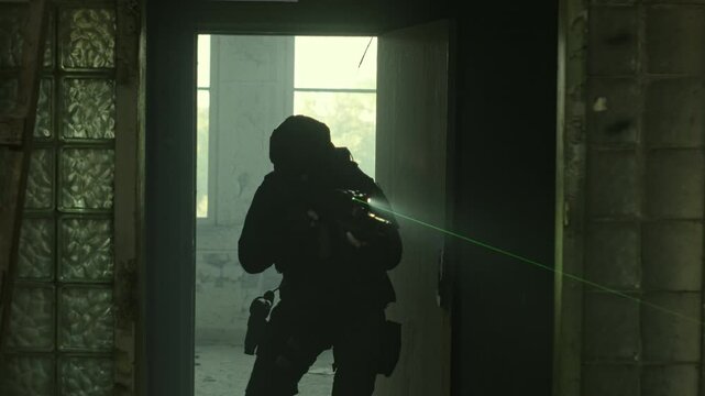 SWAT operator in all black gear and an assault rifle breaching a door in an abandoned warehouse