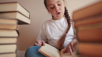 little girl in the library reading a book. education school kid science concept. a child sits on...