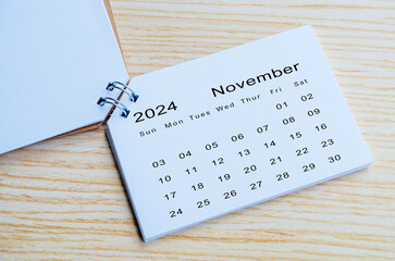 Top view of November 2024 calendar on wooden background. Calendar month of year 2024 concept