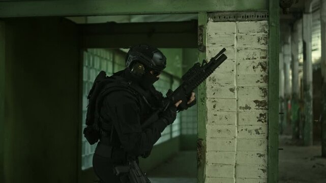 Special forces operator in black military outfit reloading his m4 assault rifle in an abandoned warehouse