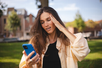 Beautiful upset woman walking outdoor in park. Sad angry female having talking conversation with...