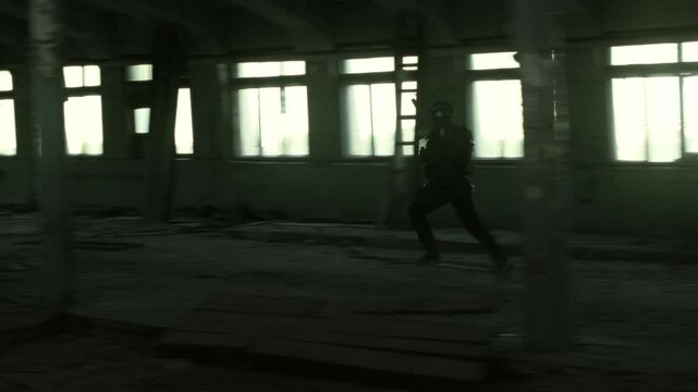 Quick reaction force operator in black military outfit and an m4 assault rifle with a green laser running in an abandoned warehouse