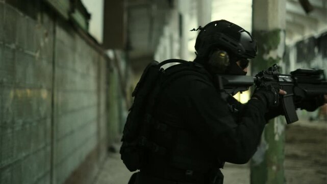 Soldier in black military outfit and an assault rifle with green laser clearing an abandoned warehouse