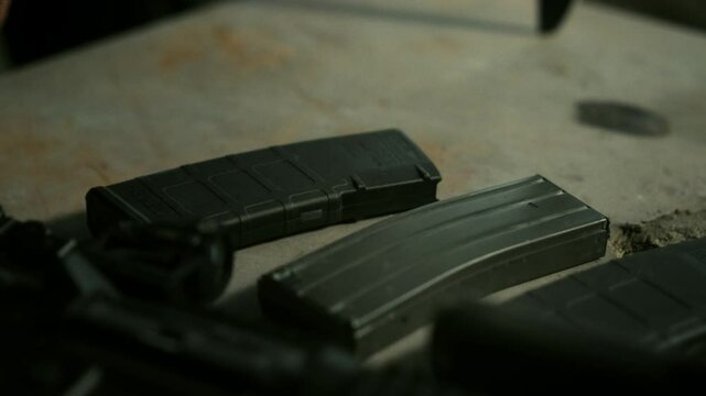 Quick reaction force specialist picking up an assault rifle magazine from a wooden table