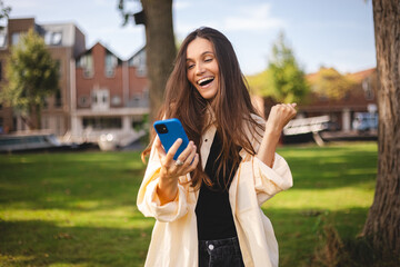 Portrait photo smiling young girl browsing internet with cellphone mobile phone wearing casual...