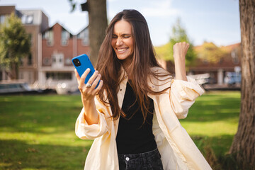 Portrait photo smiling young girl browsing internet with cellphone mobile phone wearing casual...
