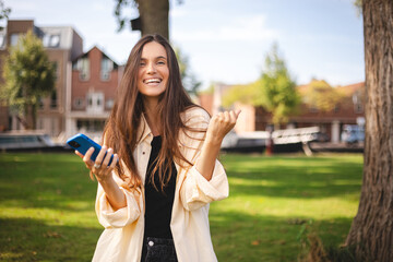 Portrait photo smiling young girl browsing internet with cellphone mobile phone wearing casual...