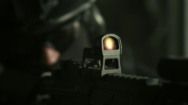 Special forces operator in all black military gear checking his collimator sight on an m4 assault rifle
