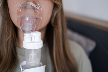 A girl breathes with the help of a nebulizer inhaler for the treatment of colds and coughs during...