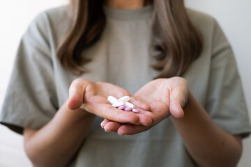 Girl holding pills in her hands, close-up. Treatment of colds during the disease season, healthy lifestyle