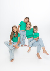 Obraz premium Front portrait of a modern family concept. Young mom with her daughters, posing in studio. Enjoy time together. 