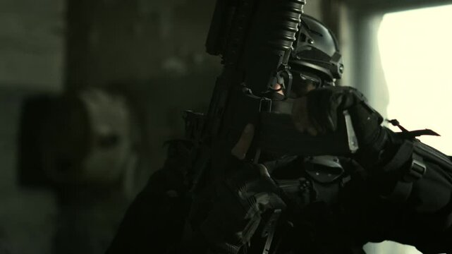 Quick reaction force operator in black stealthy outfit inserting a magazine in his m4 assault rifle