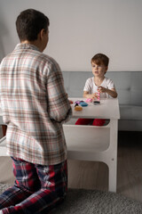 middle aged mother helps a little son to sculpt figurines from plasticine. Children's creativity and happy family