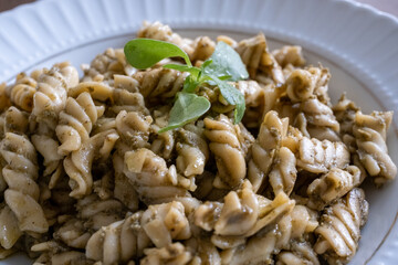 pasta with pesto sauce on brown background in close-up
