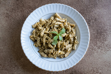 pasta with pesto sauce on brown background in close-up