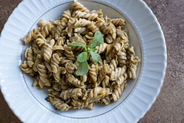 pasta with pesto sauce on brown background in close-up