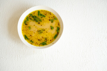 fish soup with vegetables and lemon in white bowl close-up