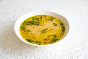 fish soup with vegetables and lemon in white bowl close-up