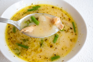 fish soup with vegetables and lemon in white bowl close-up