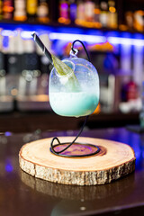 Photograph of a blue cocktail with a hanging glass. Concept of cocktails with a hanging shape.