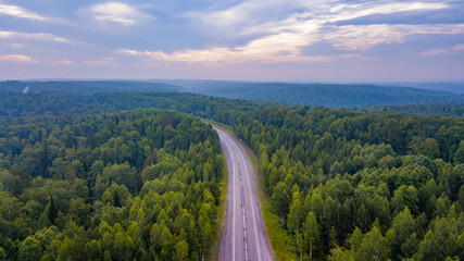 Aerial view of a road through the forest at sunset
