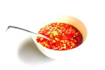 Red fresh chilli soak in fish sauce Thai original style seasoning in cup with small spoon on white background.