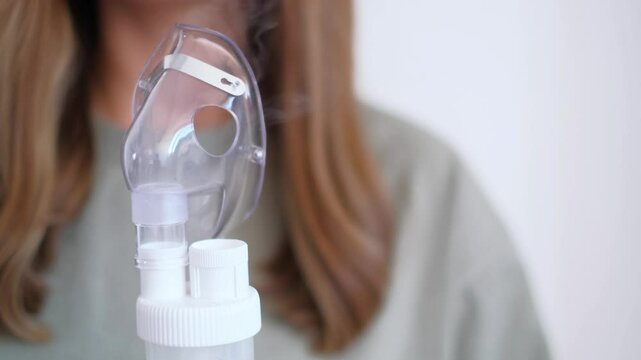 The girl turned the inhaler, nebulizer, is preparing for a home procedure, treatment of colds in the season of illnesses