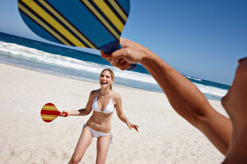 Couple, tennis and beach play by waves together for fun, holiday or bonding with sports and exercise in nature. Happy people, game and Miami ocean with vacation, adventure and travel with trip